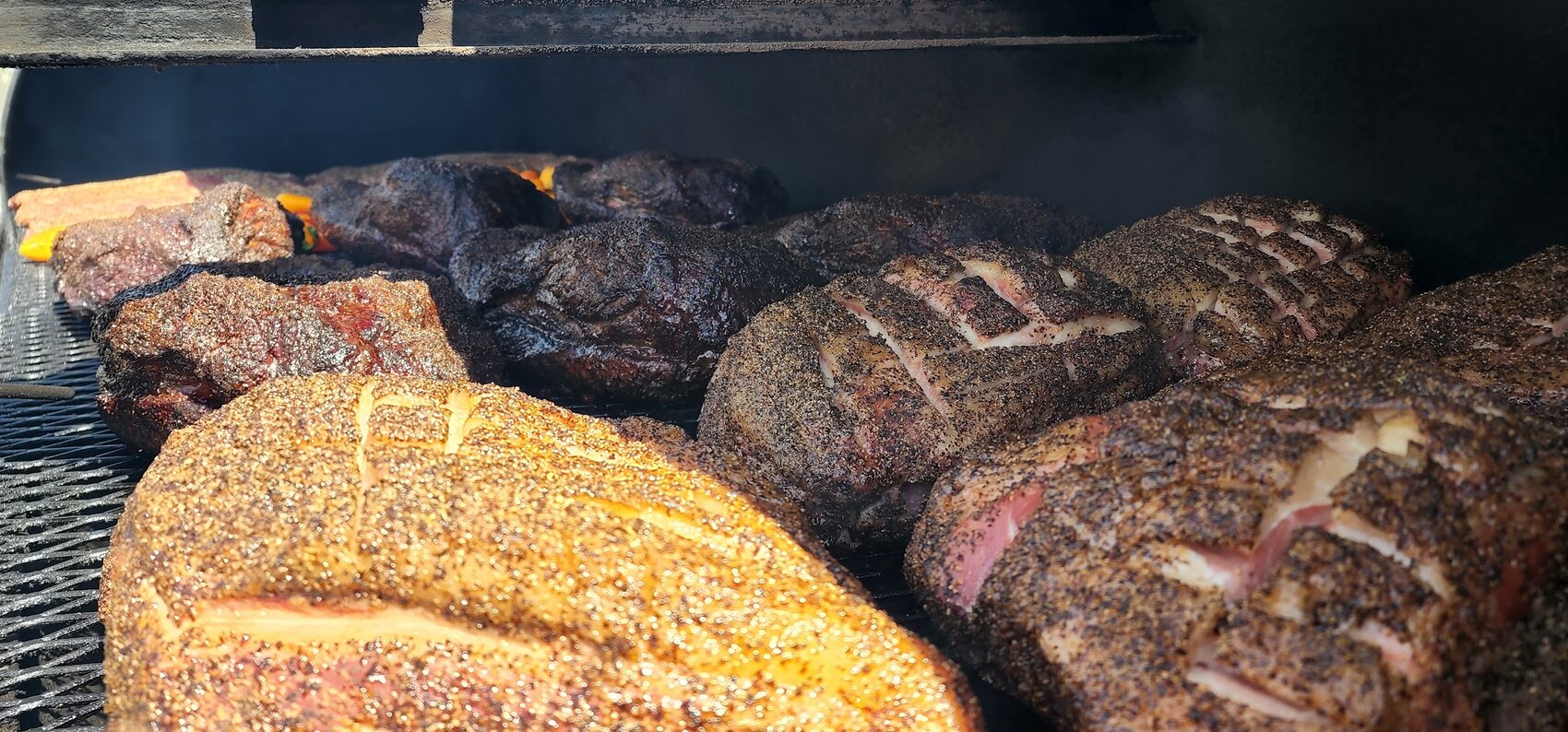 Briskets and pork resting on the smoker grate